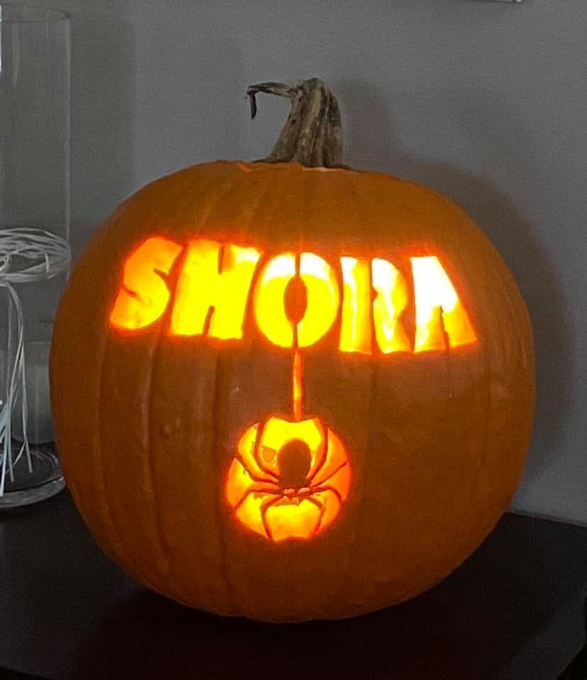Glowing SHORA jack-o'-lantern carved pumpkin with spider design